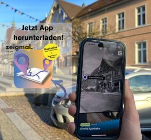 Hand hält Smartphone, auf dem die Zeigmal App geöffnet ist, in die Luft. 