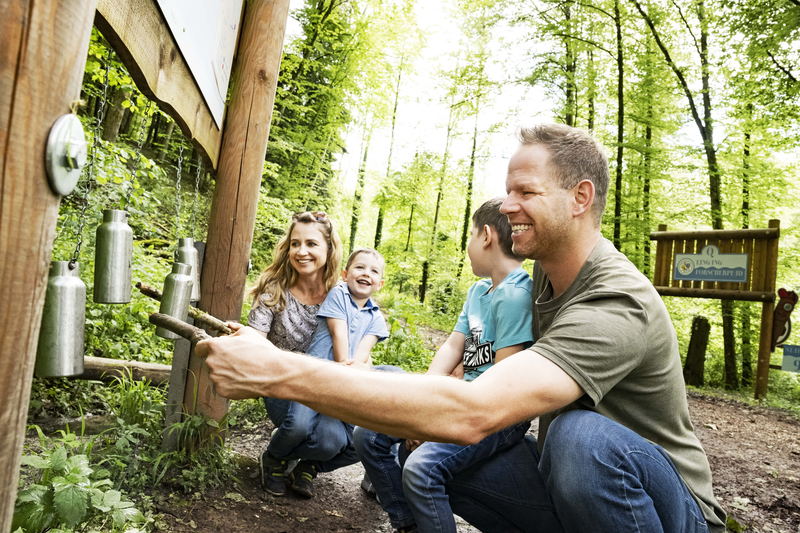 Foto: Ilja Mess Familie spielt an Erlebnisstation mit Flaschen