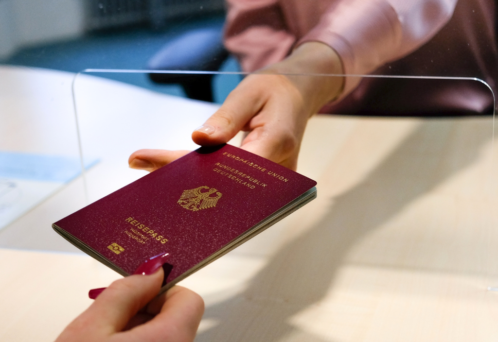 Reisepass beantragen Eine Hand übergibt einen Reisepass